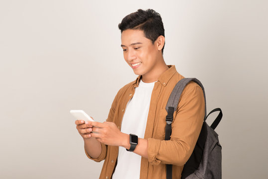 Young Asian Student Texting On Cell Phone Isolated On White Background