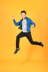 Young happy Asian teen jumping welcomely isolated on orange studio background