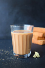 Tea Time Food - Healthy Wheat rusk served with Indian hot cardamom flavored or masala tea, over black background with whole cardamom. Copy space