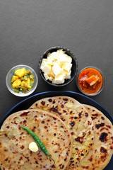 Indian Food - Aloo Paratha or Indian Potato stuffed Flatbread. Served with butter for breakfast, pickle and masala potatoes among with Indian Tea or masala chai.  with copy space.