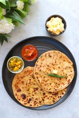 Indian Food - Aloo Paratha or Indian Potato stuffed Flatbread. Served with butter for breakfast, pickle and masala potatoes among with Indian Tea or masala chai.  with copy space.