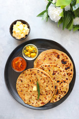 Indian Food - Aloo Paratha or Indian Potato stuffed Flatbread. Served with butter for breakfast, pickle and masala potatoes among with Indian Tea or masala chai.  with copy space.