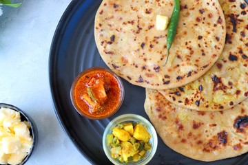 Indian Food - Aloo Paratha or Indian Potato stuffed Flatbread. Served with butter for breakfast, pickle and masala potatoes among with Indian Tea or masala chai.  with copy space.