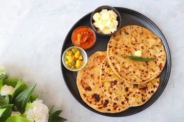 Indian Food - Aloo Paratha or Indian Potato stuffed Flatbread. Served with butter for breakfast, pickle and masala potatoes among with Indian Tea or masala chai.  with copy space.