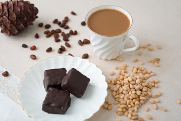Rich winter hot chocolate with cinnamon sticks and walnuts in blue enamel mug on wooden board over grey concrete background, selective focus, square crop