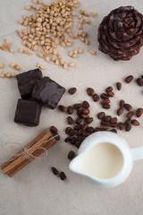 Rich winter hot chocolate with cinnamon sticks and walnuts in blue enamel mug on wooden board over grey concrete background, selective focus, square crop