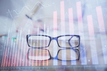 Hand taking notes in notepad. Forex chart holograms in front. Concept of research. Double exposure