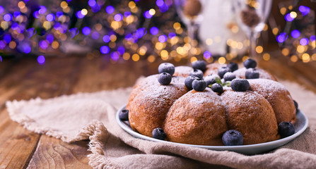 Christmas cake with berries and icing sugar on a wooden background. Traditional pastries in Italy.