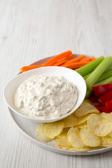 Homemade Caramelized Onion Dip with Potato Chips, Celery, Pepper and Carrot on a white wooden background, low angle view. Copy space.