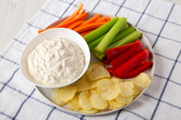 Homemade Caramelized Onion Dip with Potato Chips, Celery, Pepper and Carrot on cloth, low angle view. Close-up.