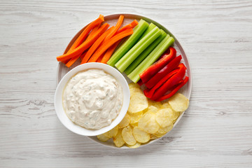Homemade Caramelized Onion Dip with Potato Chips, Celery, Pepper and Carrot on a white wooden...