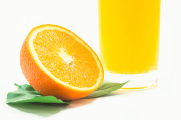 A cup of orange juice and cut orange on  white background.