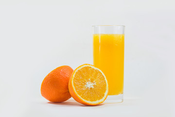 A cup of orange juice and cut orange on  white background.