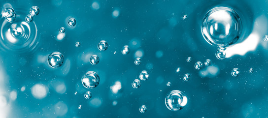 Bubbles of air on the smooth surface of blue water as an abstract background