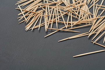 Scattered wooden toothpicks lies on black concrete desk on kitchen. Space for text
