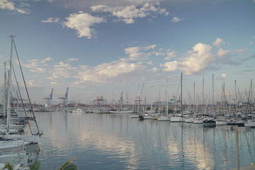 Luxury power boats in the Royal Marina in Valencia Spain, some moored,others sail on the sea. The...