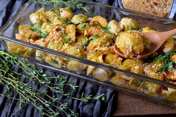 Roasted brussels sprouts topped with nut sprinkle in a glass baking dish