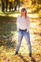 Outdoor close up portrait beautiful blonde girl relax on the ground in the autumn forest in sunny warm day