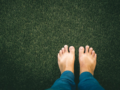 Bare Feet Standing On The Floor Of The Artificial Turf. Standing On Grass.