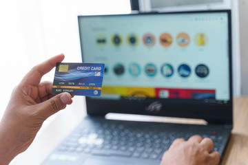 Man holding mock up banking card  while using and typing on laptop. Shopping and payment online.