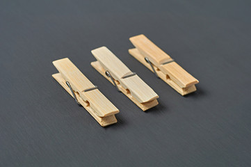 Row of three wooden clothespins lies on dark concrete desk in bathroom. Close-up