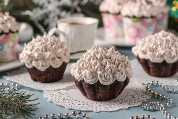 Homemade chocolate cupcakes with cream and a cup of coffee arranged on a light blue background, horizontal orientation