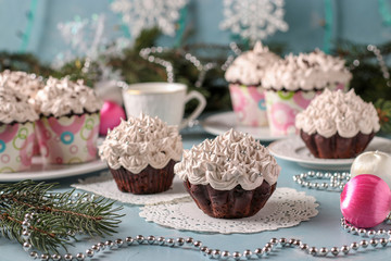 Homemade chocolate cupcakes with cream and a cup of coffee arranged on a light blue background, horizontal orientation, Festive still life