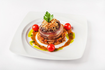 Close-up of beef tenderloin in bacon in a restaurant. Beef roll with bacon on a pillow on a white plate and copy space.