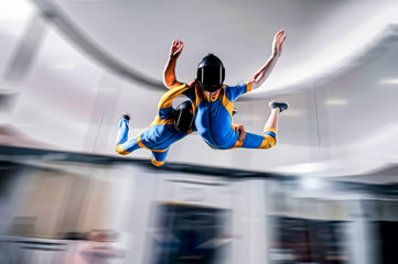 Speed. Extreme people prefere sky sport. Fly men perfoms trick in air. Parachutist in blue and yellow suit is in free fall. Skydiving is sport without rules.