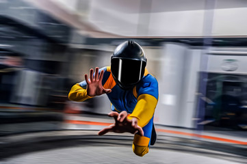 Speed. Extreme people prefere sky sport. Fly men perfoms trick in air. Parachutist in blue and yellow suit is in free fall. Skydiving is sport without rules.