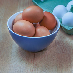 several fresh chicken eggs in a ceramic cup on a wooden background. Healthy eating concept