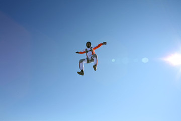 Up. Fly men is a pilot of his body in air. Extreme people prefer skydiving. Parachutist in white and orange suit. Free lifestyle.