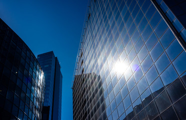 The sun's rays are reflected in the glass of a modern office skyscraper