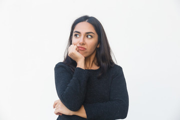Pensive disappointed woman leaning chin on hand, looking away. Beautiful young woman in casual sweater posing isolated over white background. Thinking or advertising concept