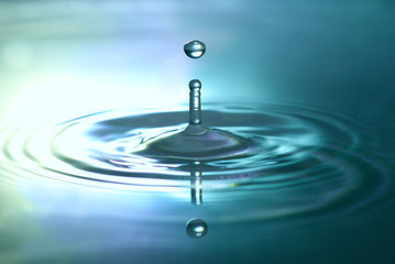 close up of a waterdrop splashing into metallic blue reflecting water