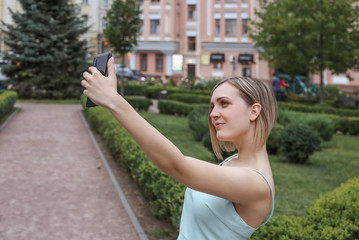 sharing happy selfie. Handsome young smiling woman in casual wear taking selfie using his smart phone while standing outdoors