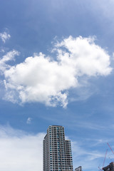 Fototapeta na wymiar Beautiful white fluffy cloud formation on vivid blue sky in a sunny day above tower in big city, a part of Bangkok in Thailand