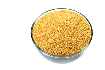 yellow mustard seeds in glass bowl isolated on white background