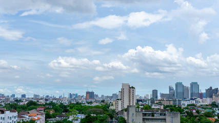Fototapeta premium Beautiful white fluffy cloud formation on vivid blue sky in a sunny day above big city, view from rooftop