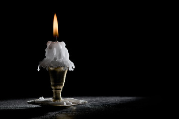 molten, burning candle on a metal candlestick