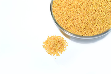 yellow mustard seeds in glass bowl isolated on white background