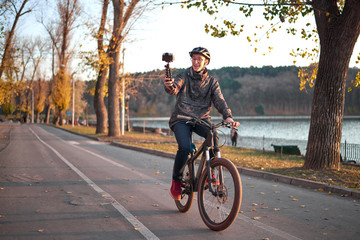Young cyclist vlogging in the park with a bicycle in the background