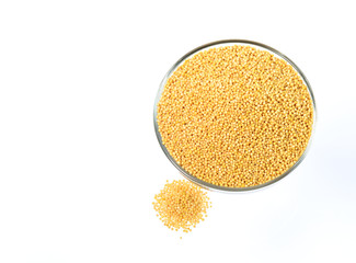 yellow mustard seeds in glass bowl isolated on white background