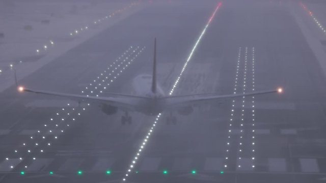An airliner lands on a wet runway at San Diego International Airport after a rain storm in tricky crosswind conditions at dusk.