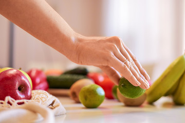 Woman hands holding green lime with other fruits on background