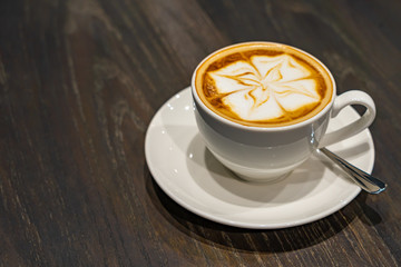 Isolated beautiful cappuccino milk foam art coffee on wooden table