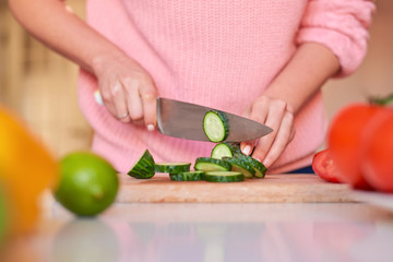 Woman hands cutting cucumbers with knife