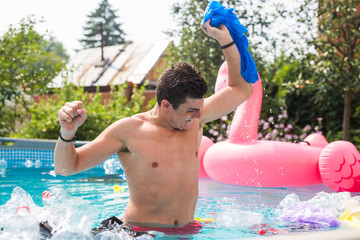 Ecology, plastic trash, environmental emergency and water pollution - shocked man standing in a dirty swimming pool