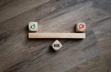 Cubes dice with thumbs up and down and risk on wooden background