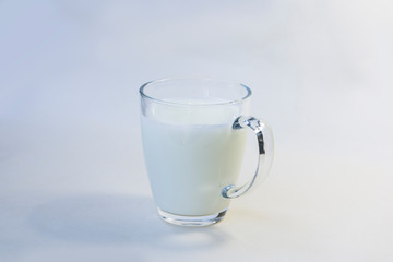 A cup of soy milk stands alone on a pale yellow background.